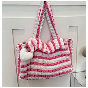 Gros plan du sac cabas en tissu à bulles rayé rose et blanc avec breloque cœur