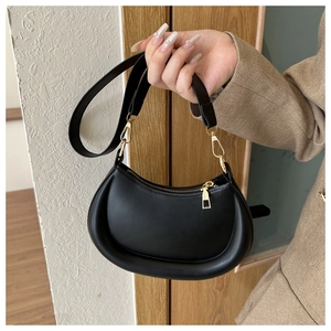 Detail of minimalist black crescent bag with smooth leather finish and gold zipper hardware