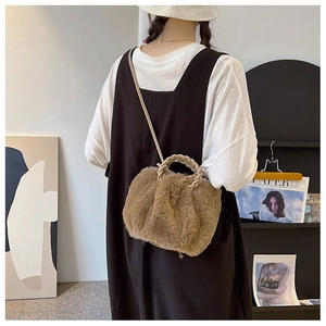 Brown faux fur crossbody bag with braided handles worn over a black dress back view