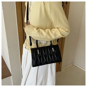 Detail of black matelassé quilted handbag with silver hardware and dual top handles