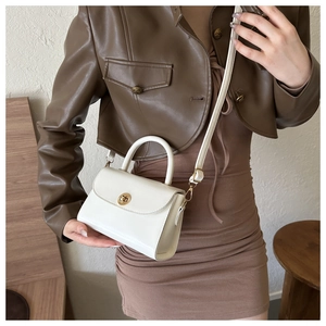 Detail of white PU leather crossbody bag with golden round metal lock worn by a model