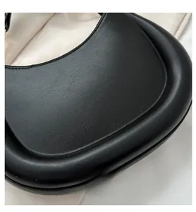 Close-up of minimalist black leather crescent bag with smooth edges and rounded silhouette