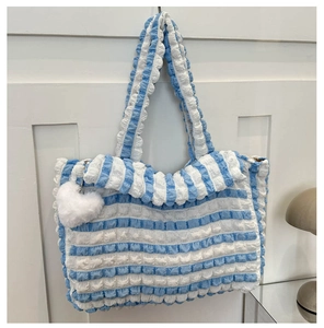Détail du sac cabas à rayures bleues et blanches avec texture bulle et breloque cœur