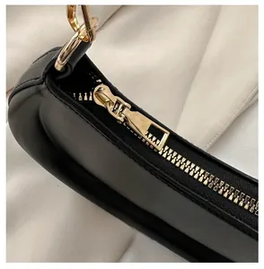 Close-up of golden metal zipper and black leather detail on the crescent bag