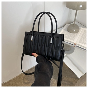 Close-up of black pleated tote bag showing detailed vertical stitching and silver hardware