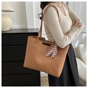 Camel tote bag with red and white plaid scarf detail on shoulder strap in interior setting