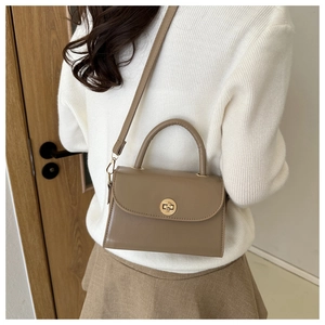 Detailed view of khaki leather crossbody bag with elegant gold circular swivel lock