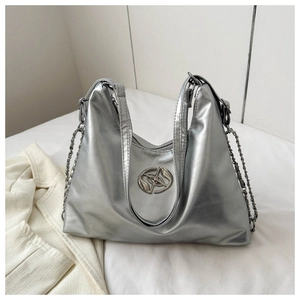 Close-up of shiny silver metallic tote bag featuring double handles and chain decorations