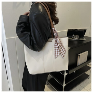 Detail of cream tote bag with brown handles and elegant brown checkered silk scarf accent