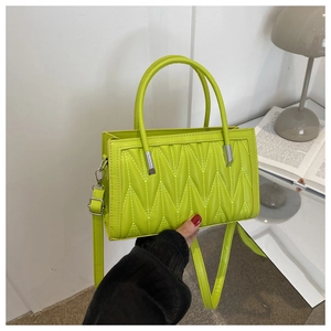 Detail view of the neon green quilted texture and dual handles on this stylish small bag