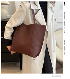 Close-up of a large dark brown lychee leather tote bag with elegant gold metal accents