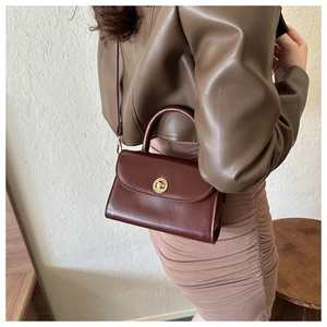 Close-up of a vintage brown leather crossbody bag with a golden metal twist lock detail