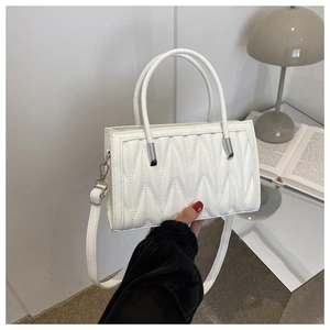 Detail of white PU leather crossbody bag featuring geometric pleated stitching and slim strap