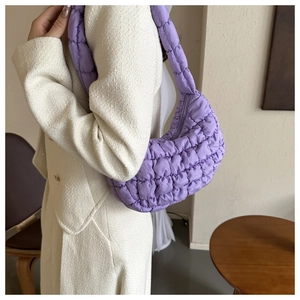 Détail du sac croissant violet matelassé montrant le tissu texturé et sa forme courbée
