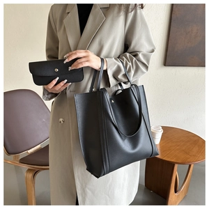 Classic black matte leather tote bag with a matching envelope clutch in a modern setting