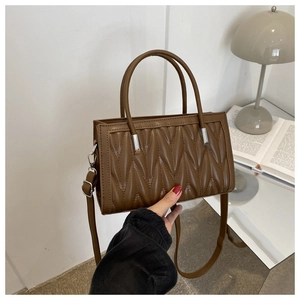 Detail of a brown matelassé crossbody bag with silver hardware and vintage texture