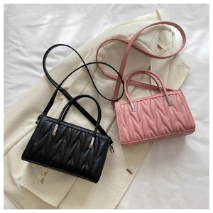 Detail view of pink and black quilted rectangular handbag with unique V-pleat texture details