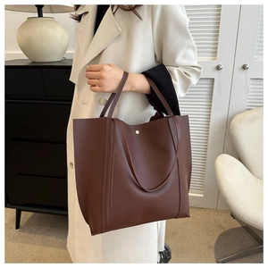 Detail of dark brown PU leather tote bag showing stitch decor and metal buckle closure