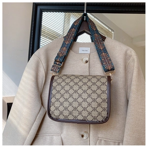 Détail du sac à bandoulière vintage avec large sangle à motifs sur manteau beige
