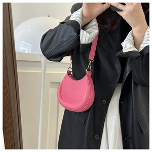 Pink crescent underarm bag shown in a mirror selfie with adjustable strap and gold hardware