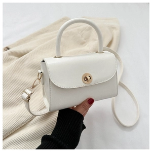 Detail of a white crossbody bag with a round gold buckle and smooth leather finish
