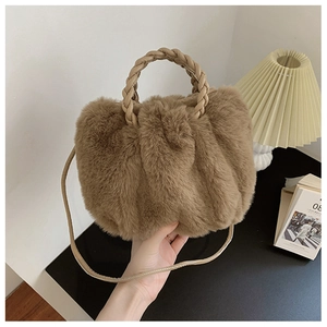 Close-up of brown plush faux fur cloud bag with woven leather handle and slim strap