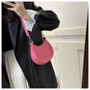 Detail view of pink crescent shoulder bag with golden hardware on model side profile