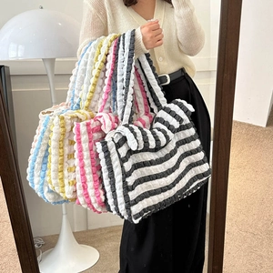 Grand sac à main texturé à bulles avec motifs rayés tenu par un mannequin devant un miroir