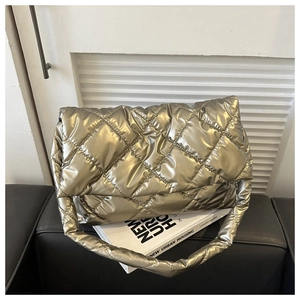 Detail of golden quilted puffer bag featuring metallic finish on an urban book background