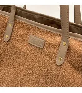 Detail of plush tote bag with brown faux shearling texture and embossed leather logo