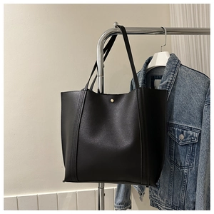 Detailansicht der schwarzen Tote-Bag aus Leder mit Goldknopf und matter Textur