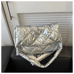 Detailed view of silver quilted space cotton shoulder bag on a sofa with modern texture