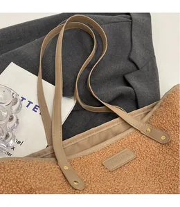 Detail of brown plush tote bag featuring a long faux leather strap and fashion label