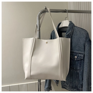 Detail der weißen Leder-Shopper-Tasche mit goldenem Druckknopf und sichtbaren Nähten