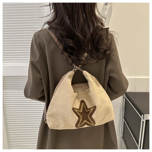 Détail du sac bandoulière en daim beige avec étoile marron porté par un mannequin