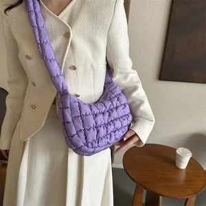 Sac bandoulière matelassé violet en nylon pour femme porté avec une veste chic