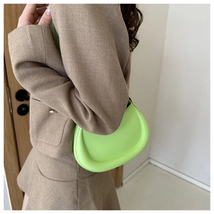 Detail of lime green half-moon shoulder bag styled with a khaki textured blazer outfit