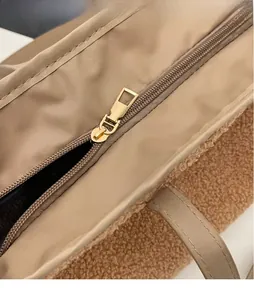 Detailed macro view of the golden metal zipper on a beige plush faux fur tote bag