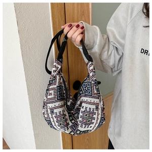 Detail of colorful woven crescent bag with geometric ethnic patterns and adjustable strap