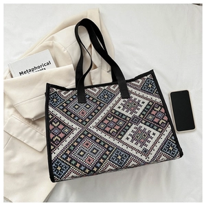 Detail of colorful geometric woven pattern on ethnic canvas tote bag with black straps
