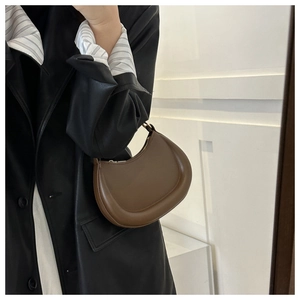 Fashionable dark brown half-moon leather shoulder bag shown on a model's arm