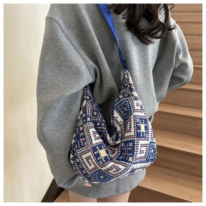 Detailed close-up of woven ethnic geometric pattern on blue hobo shoulder bag with strap