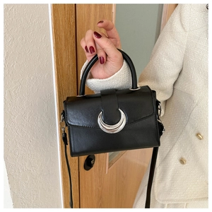 Detail of a chic black square bag featuring a distinctive silver crescent moon buckle