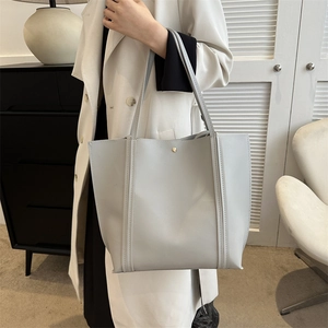 Minimalistische hellgraue Shopper-Tasche aus Kunstleder mit goldener Schnalle auf der Schulter