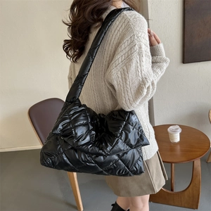 Quilted black puffer tote bag made of glossy space cotton for women on a model