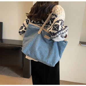 Detailed close-up of blue plush fleece tote bag with chic leather handle and fashion patch