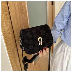 Close-up of black floral embossed crossbody bag featuring a gold horseshoe metal lock
