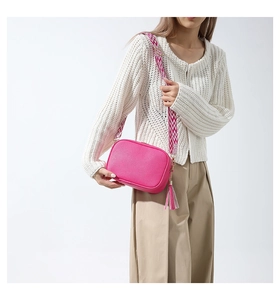 Close-up of hot pink PU leather crossbody bag with pebble texture and woven strap