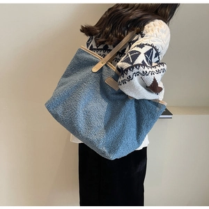 Detail of blue sherpa tote bag featuring a fashion patch and leather shoulder straps