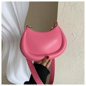 Detail of pink leather crescent bag showing puffed edges and gold metal strap hardware